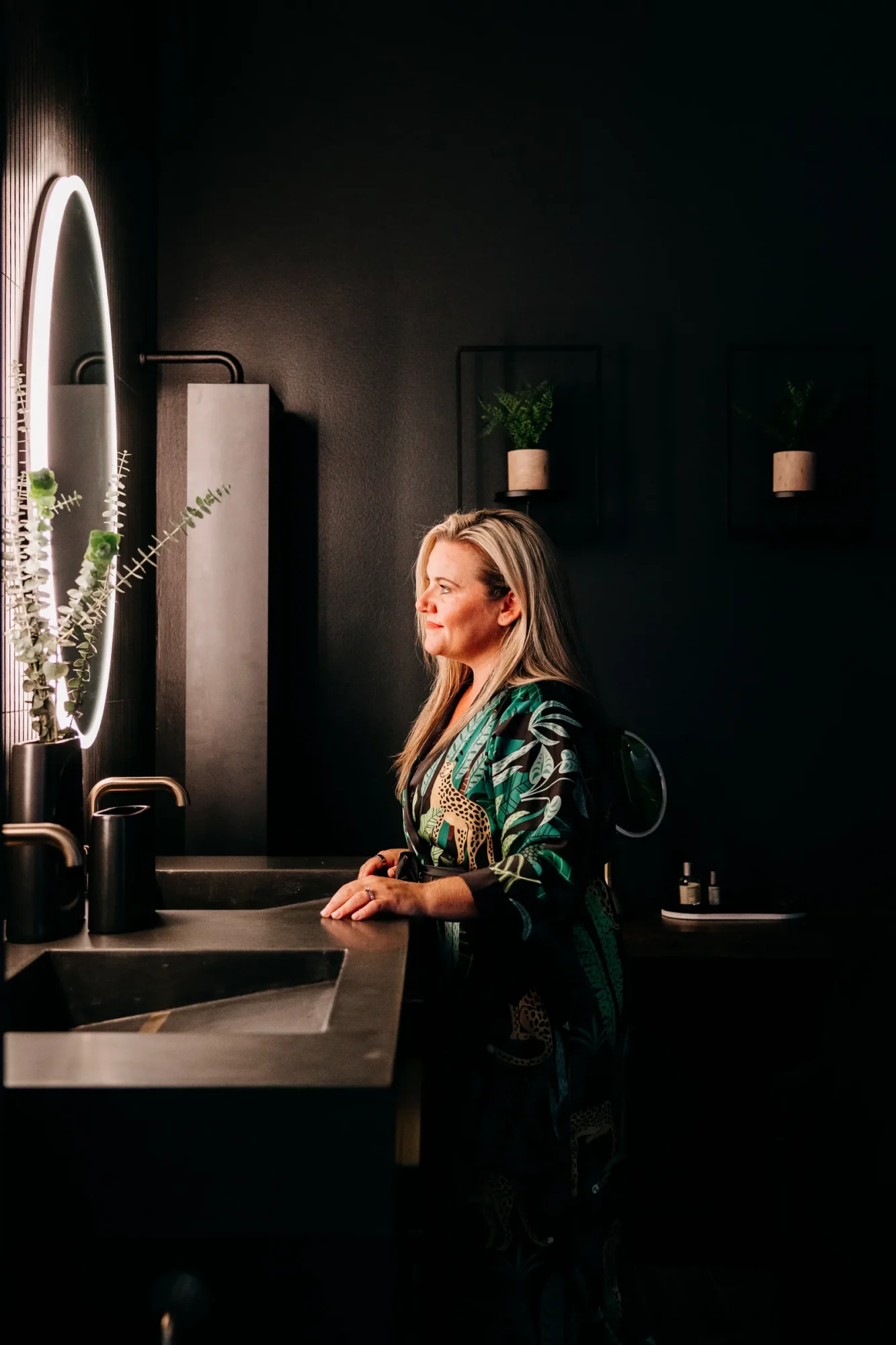 Homeowner at the vanity with an illuminated arched mirror in the primary bathroom.