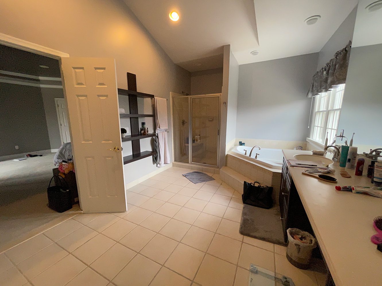 Primary bathroom before renovation, with a corner shower enclosure beside the built-in tub and vanity.